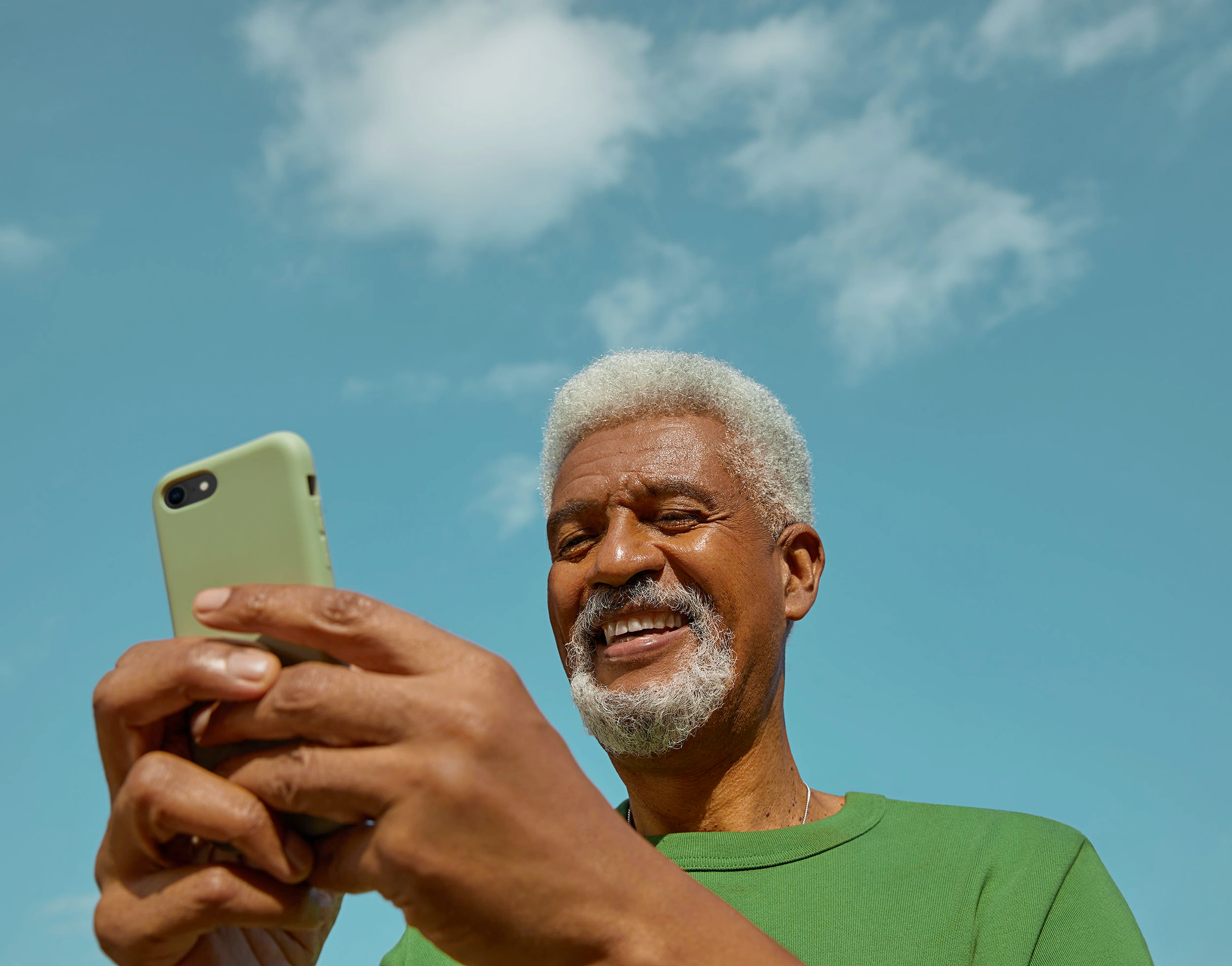 A smiling older man with grey hair on his phone