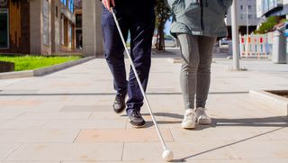 Man walking with a friend using a rolling tip cane