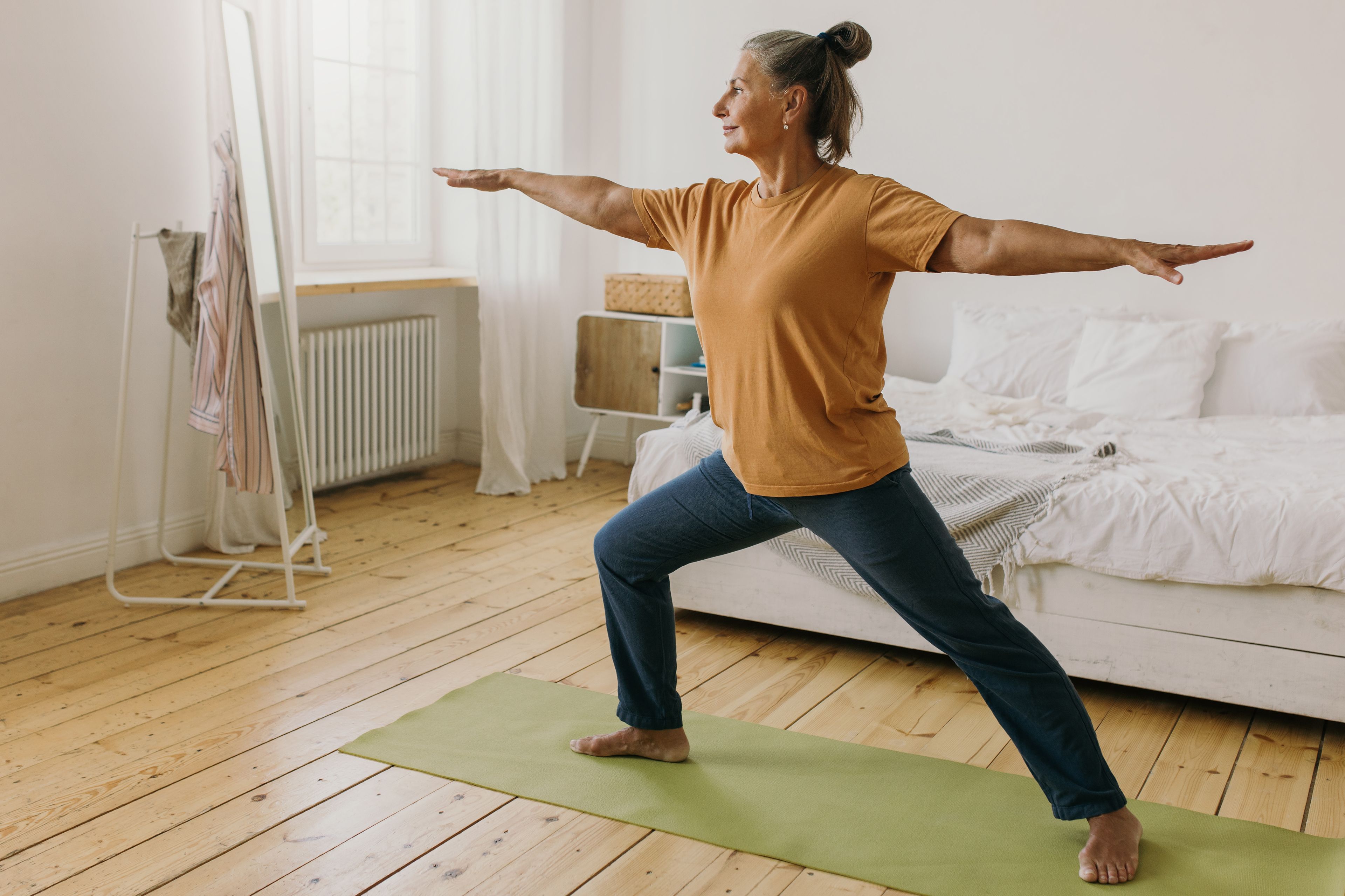 Older person doing yoga at home on yoga mat