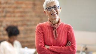 Older woman smiling with her arms crossed in an office