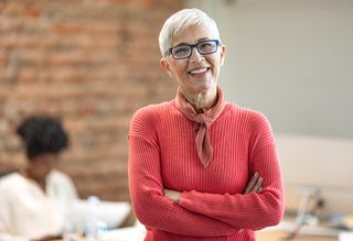 Older woman smiling with her arms crossed in an office