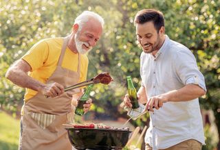 Older man barbecuing with younger peer