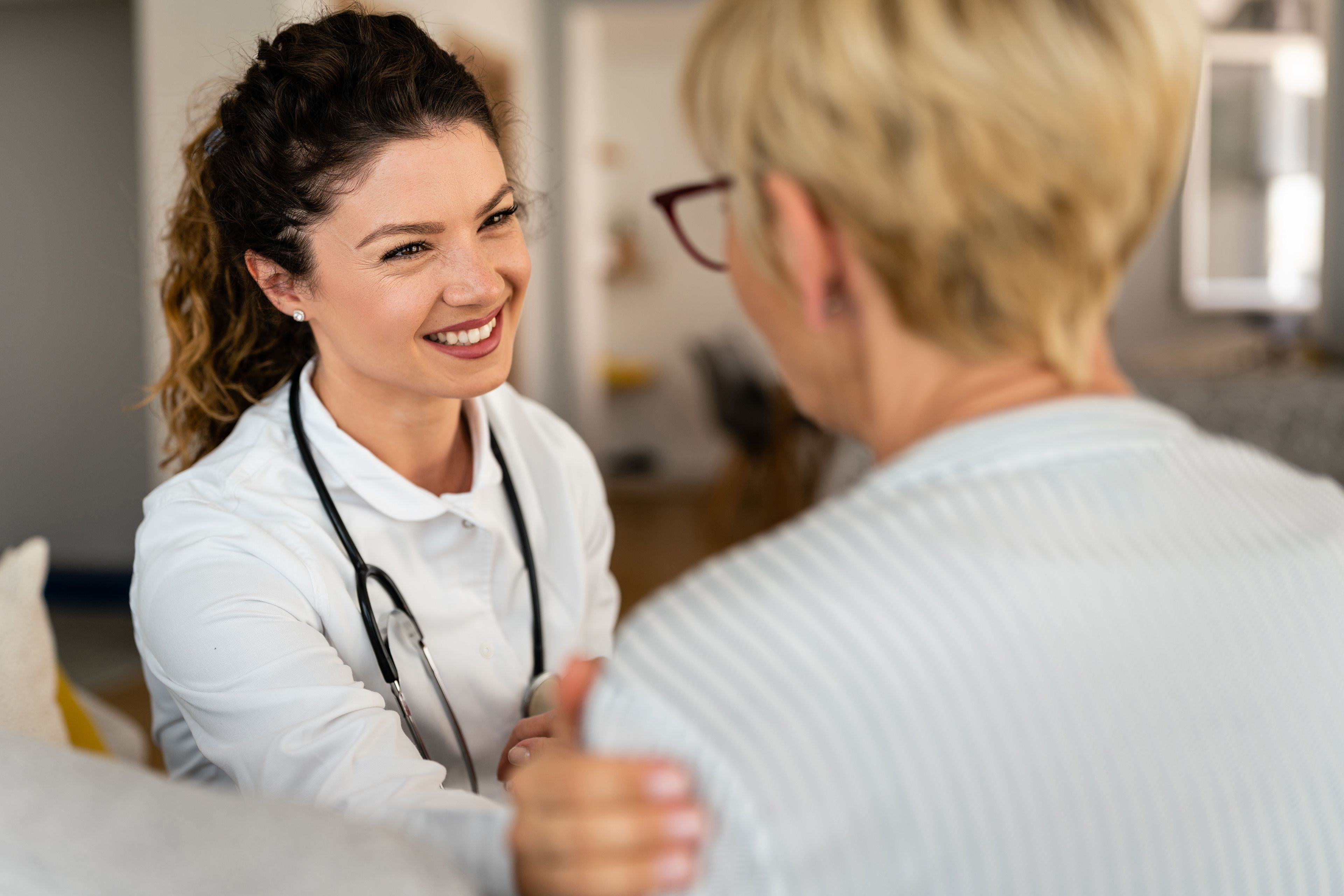 Smiling medical professional touching arm of patient in a reassuring manner