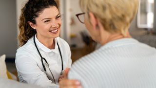 Smiling medical professional touching arm of patient in a reassuring manner