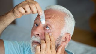 Older person using eye drops with their head titled slightly back