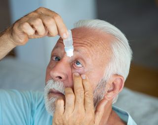Older person using eye drops with their head titled slightly back