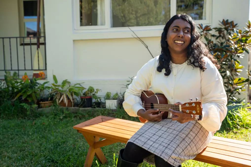  Abby playing her ukulele on a bench in her garden