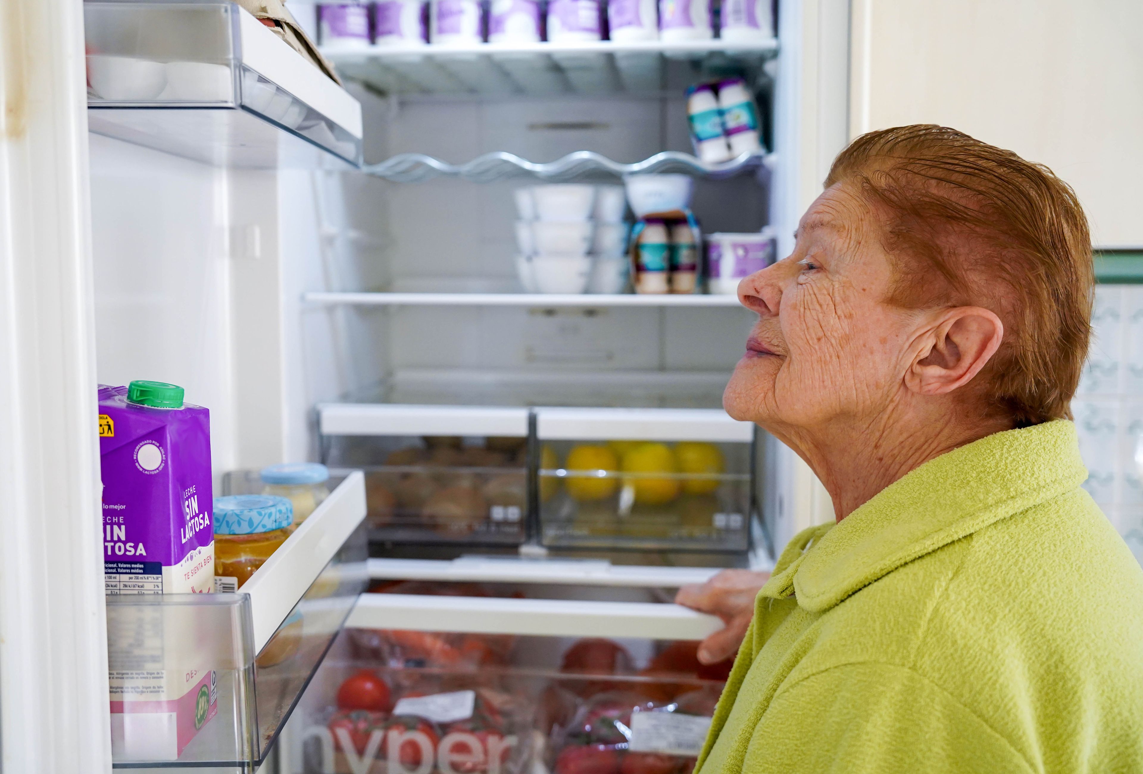 Older person looking at items in fridge