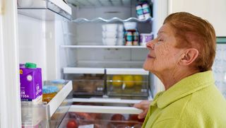 Older person looking at items in fridge