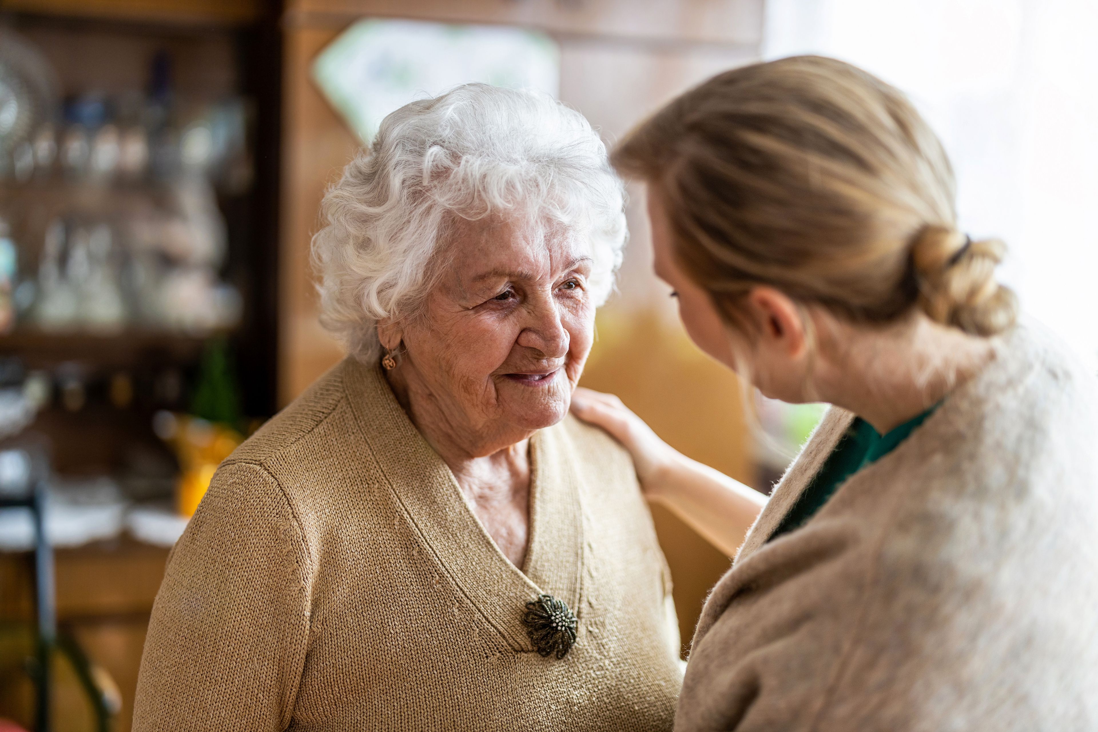 Younger person reassuring older person with hand on shoulder