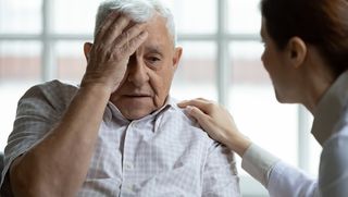 Older man with hand to his face in distress