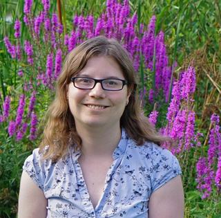 A headshot of Dr Coleman standing in a field of pink lavender.