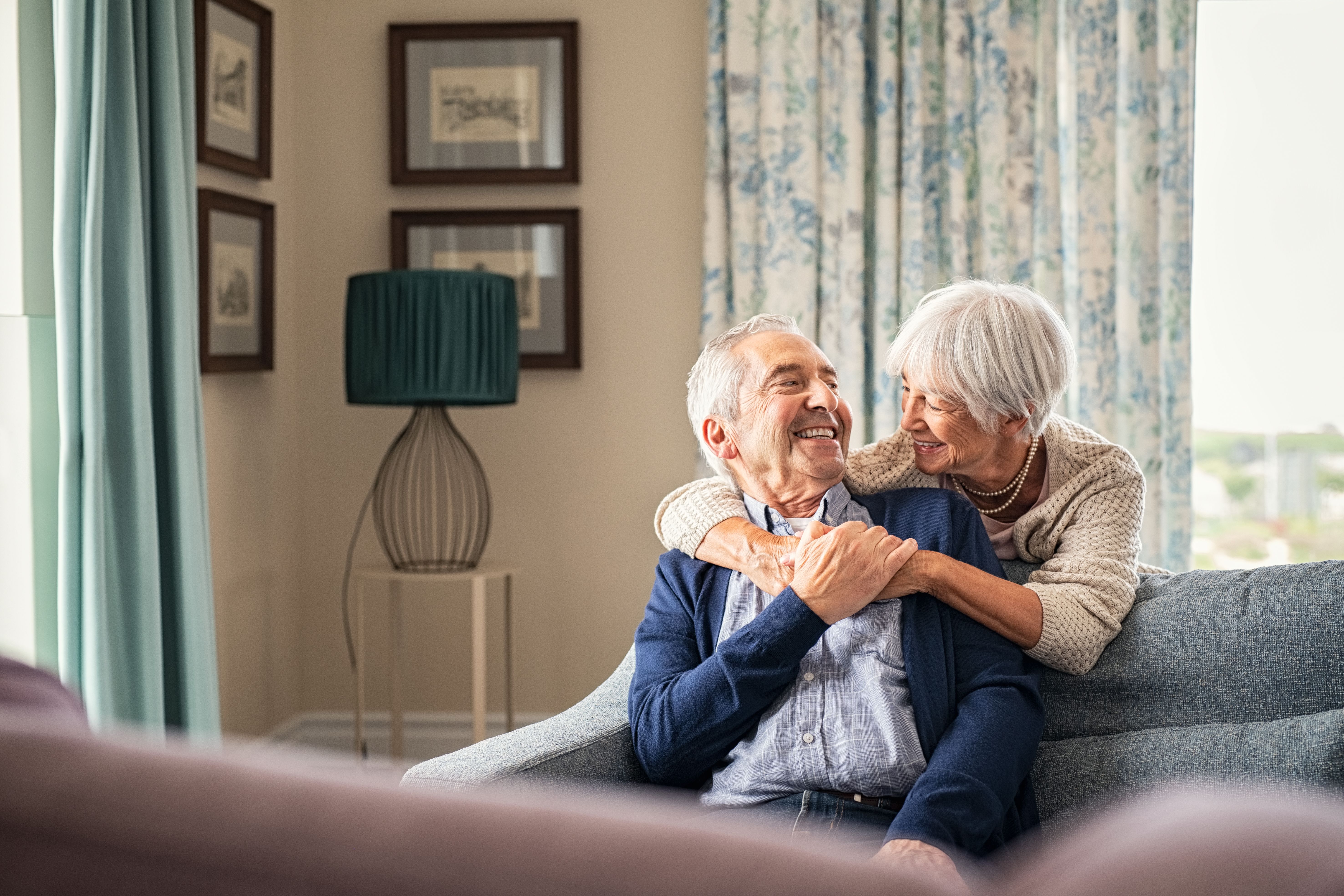 Older couple embracing over the back of a couch