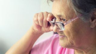Older person adjusting glasses