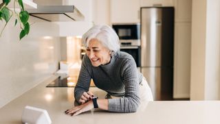 Older person using speech activated virtual assistant in kitchen
