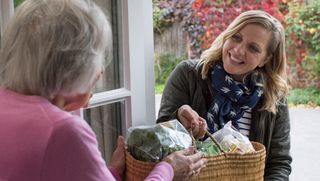 Carer delivering groceries to older person