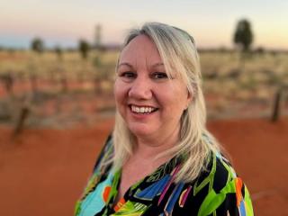 A woman smiling at the camera standing in a desert environment