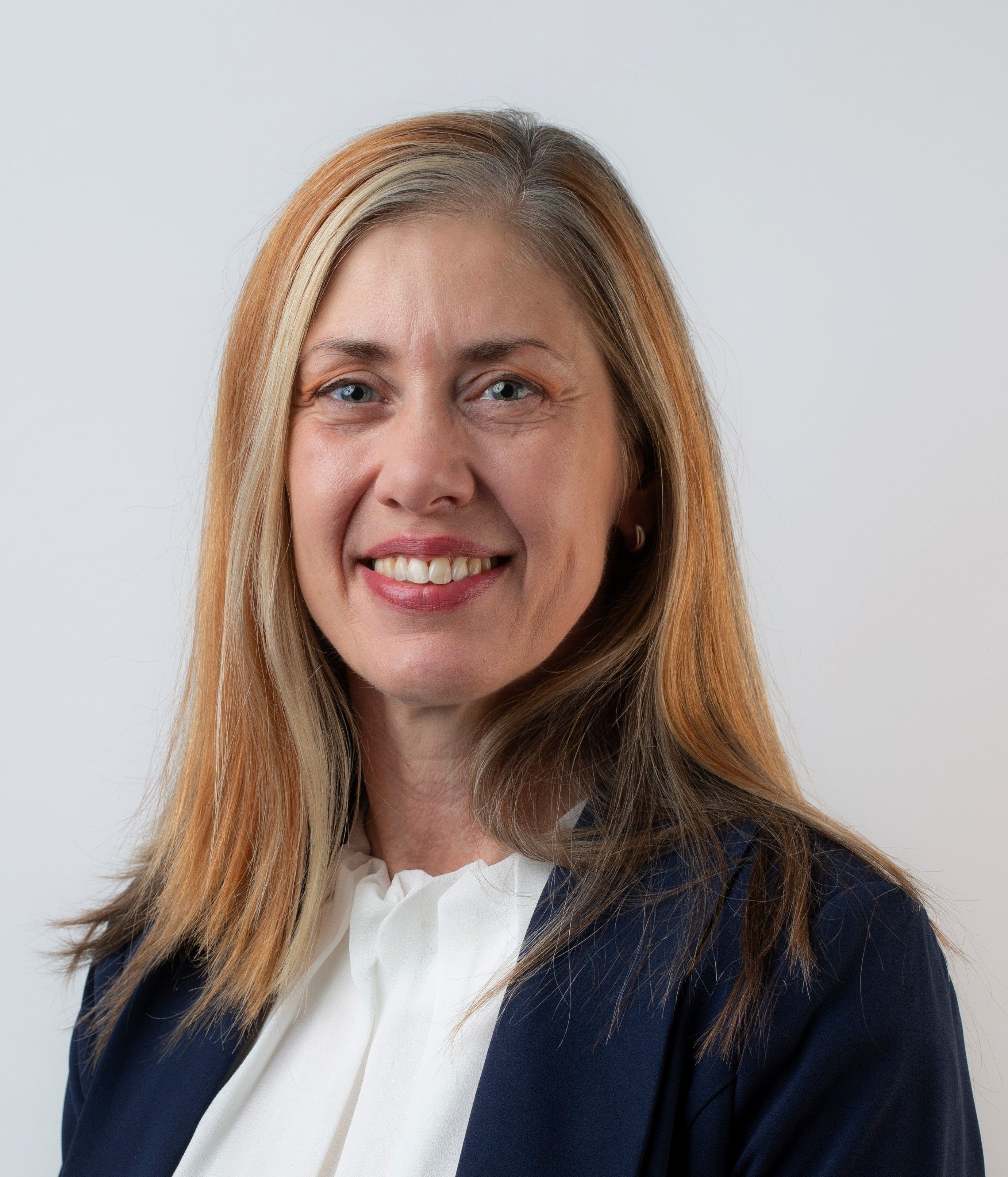 A smiling woman standing in front of a white background