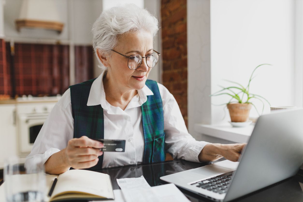Older person online shopping with a credit card in hand