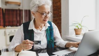 Older person online shopping with a credit card in hand