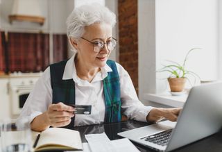 Older person online shopping with a credit card in hand