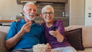 Older couple watching TV together while eating popcorn
