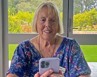 Angela smiling and using her smartphone.