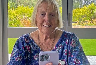 A photo of Angela wearing a blue dress and using her phone