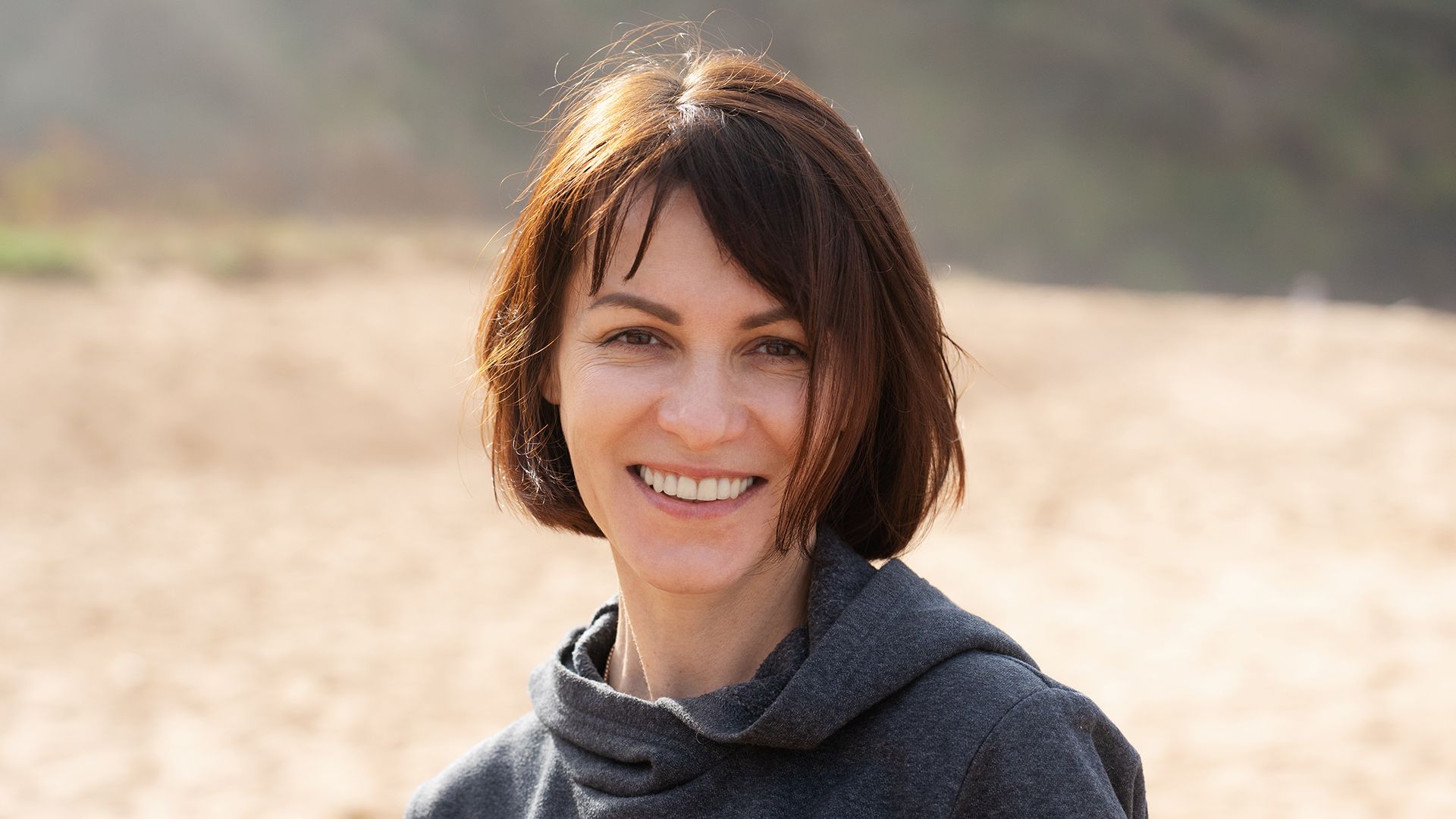 A headshot of a smiling woman at the beach