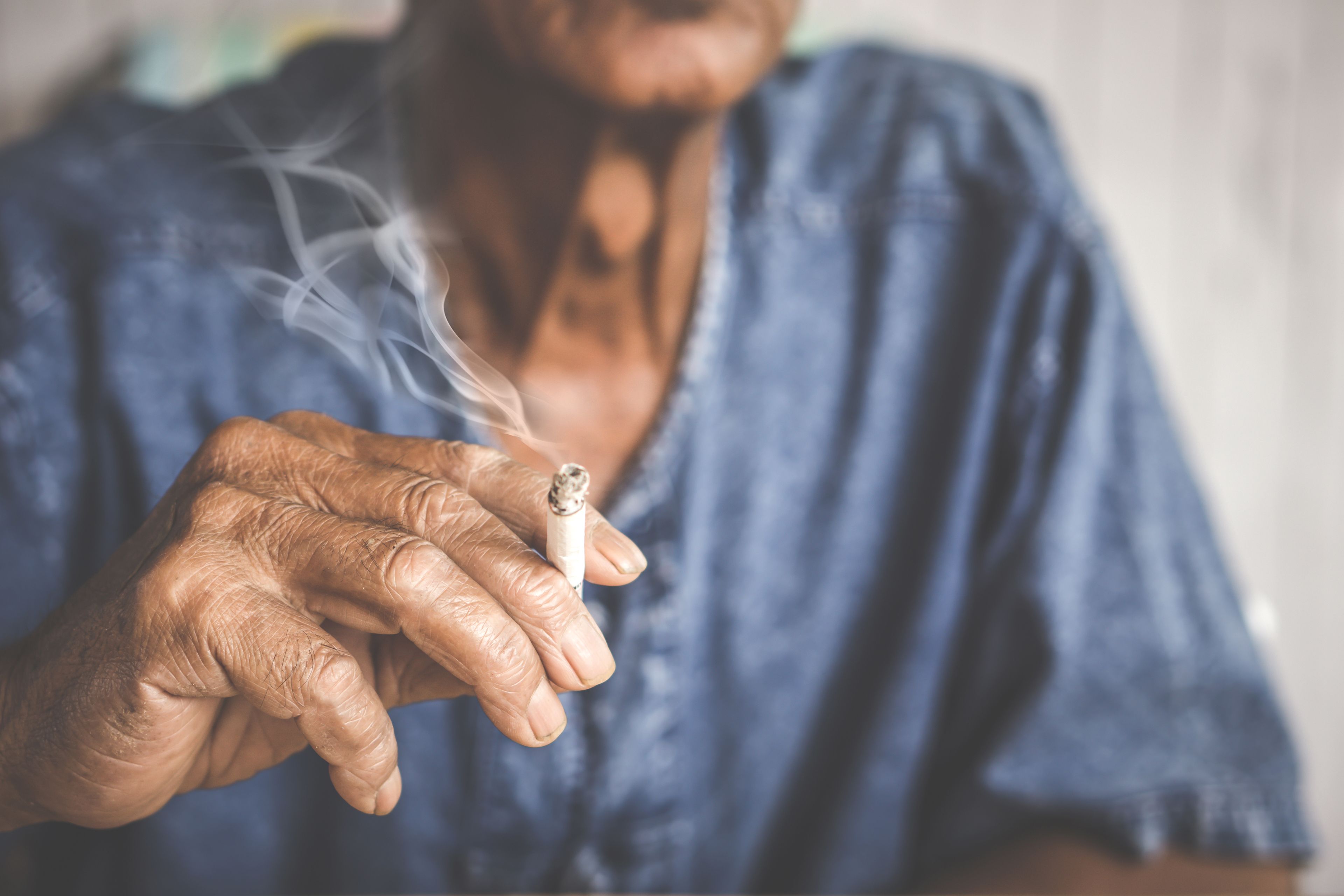 Close up on the hand of an older person while smoking