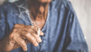 Close up on the hand of an older person while smoking