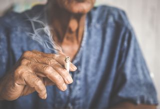 Close up on the hand of an older person while smoking