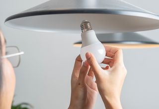 Woman changing a smart light bulb