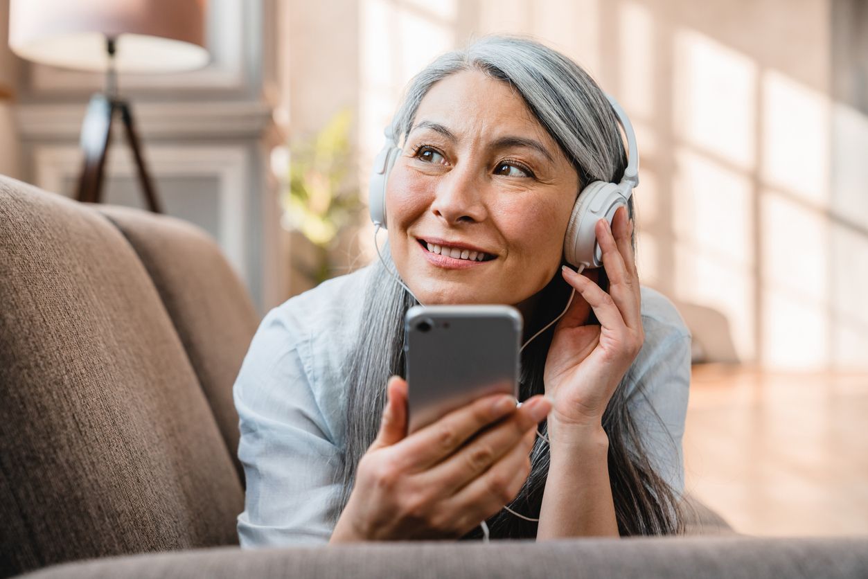 Older woman using a smartphone with headphones on