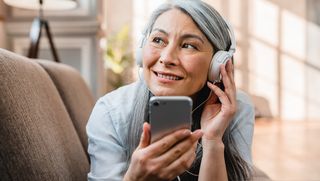 Older woman using a smartphone with headphones on