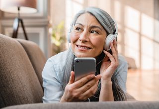 Older woman using a smartphone with headphones on