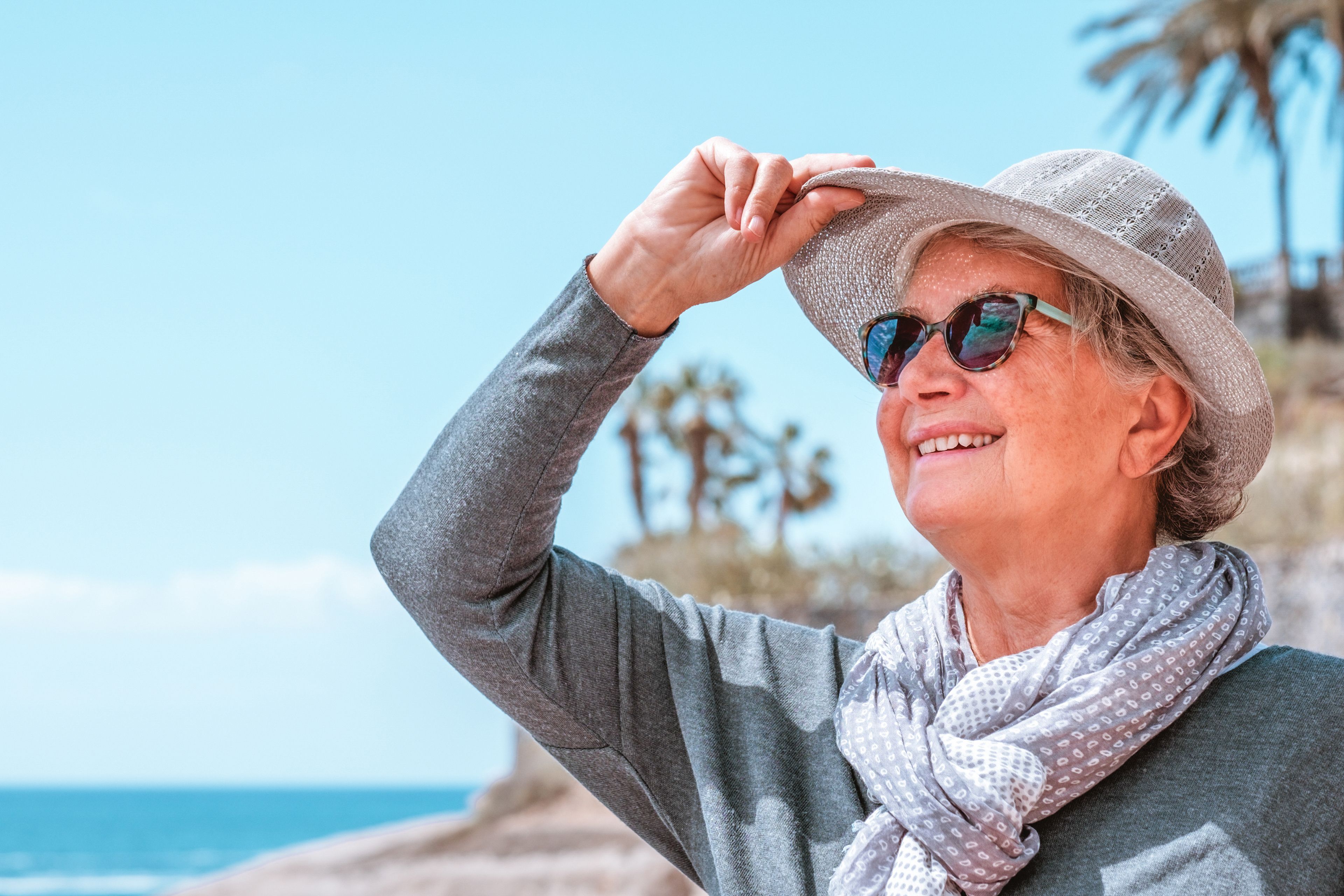Smiling person on beach wearing hat and sunglasses