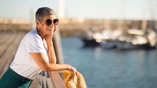 Person standing on marina wearing sunglasses looking out at the water