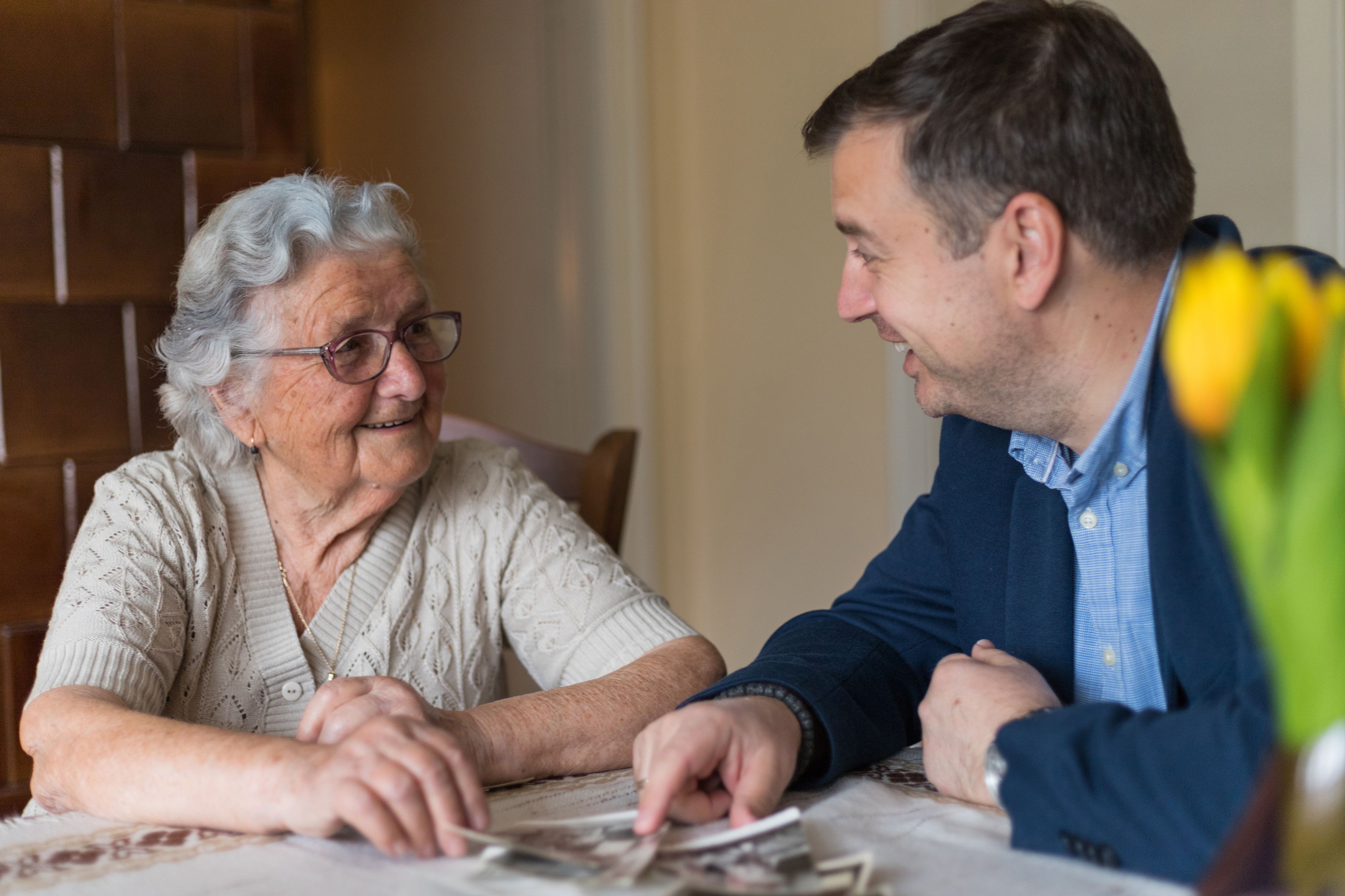Older person talking with family member while looking at old photos