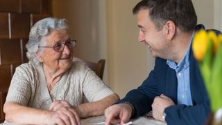 Older person talking with family member while looking at old photos