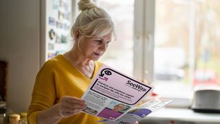 A woman reading two different SeeWay flyers.