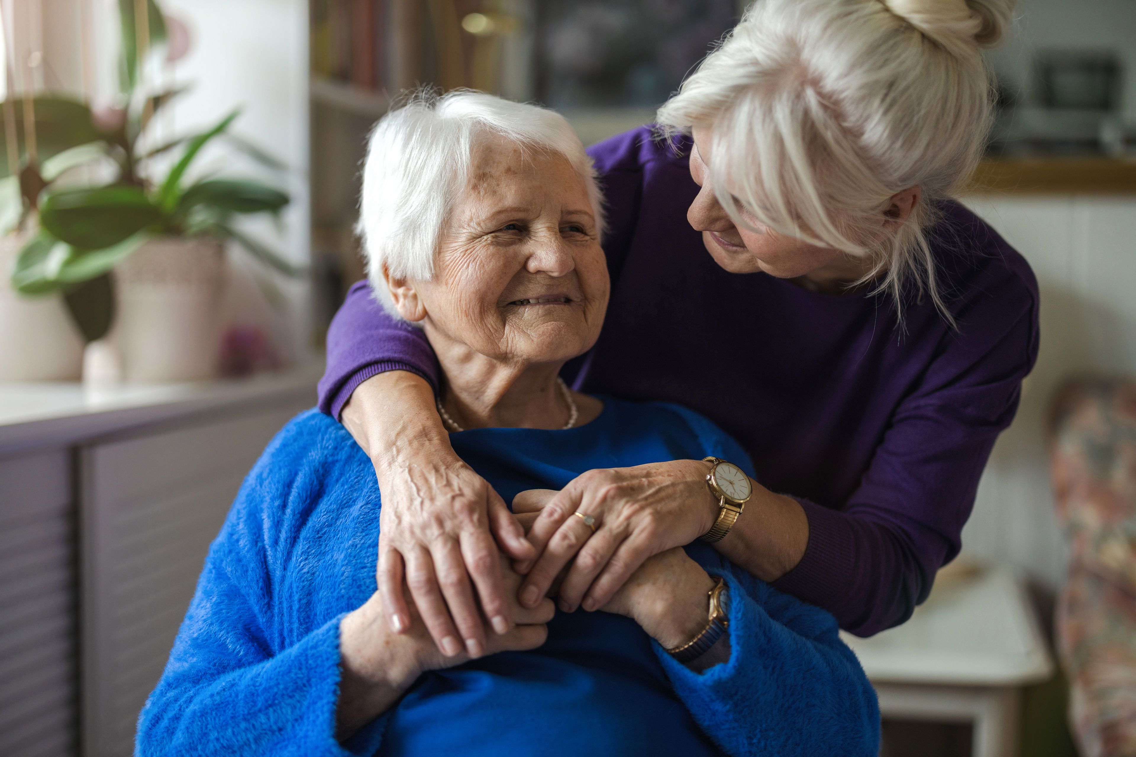 Daughter hugging smiling older mother
