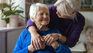 Daughter hugging smiling older mother