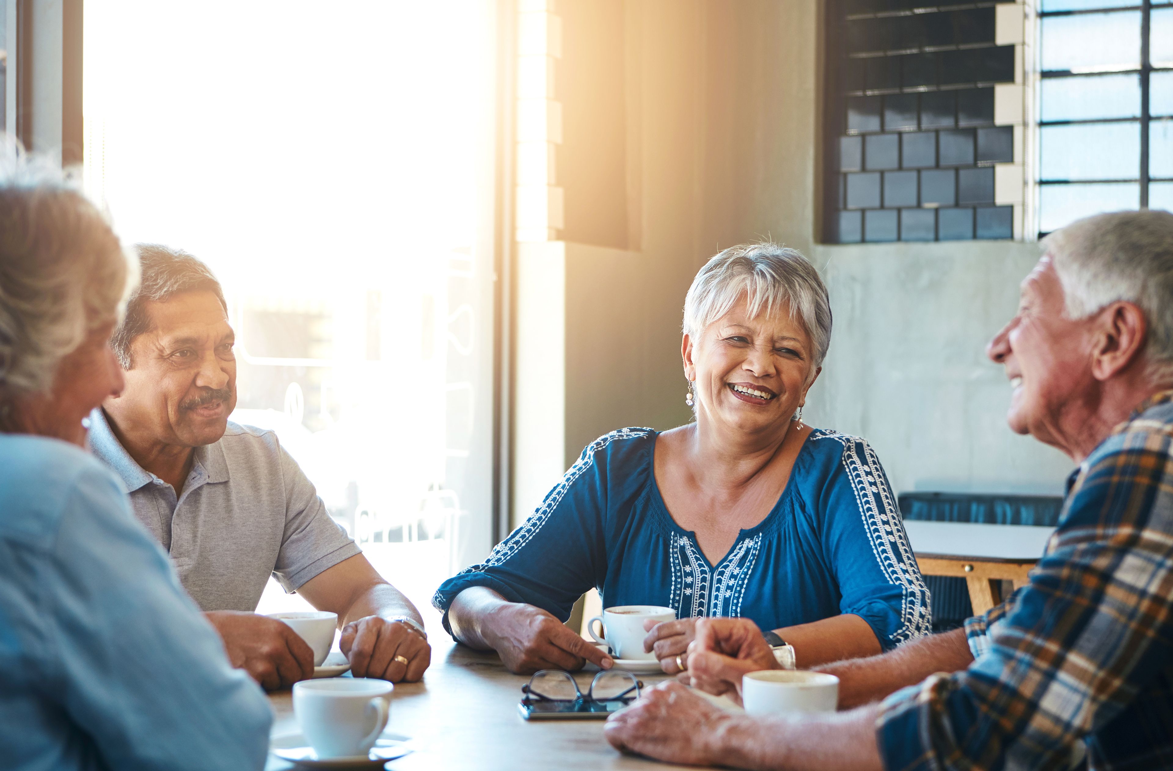 Group of four older people talking and having coffee