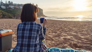 Woman drinking a mug of coffee on the beach