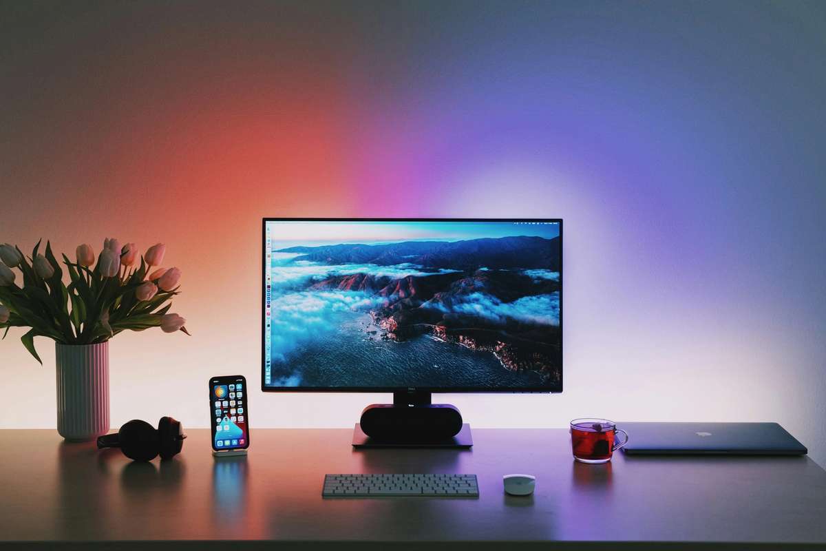 Modern desk setup with a monitor, keyboard, and ambient RGB lighting in a contemporary workspace