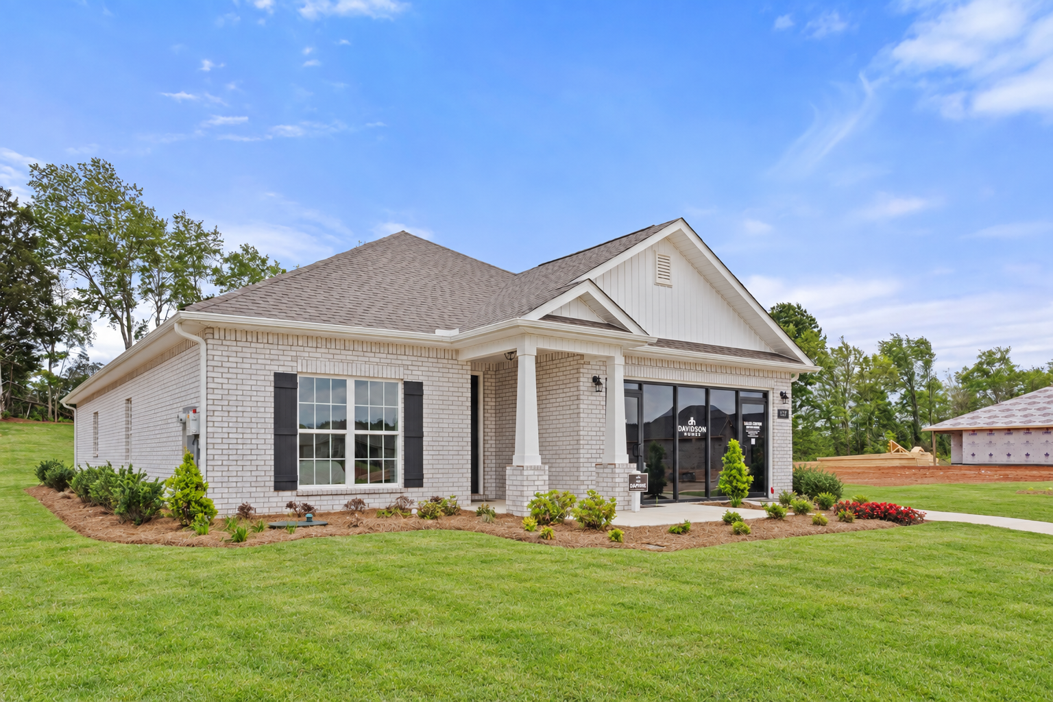 Davidson Homes sales center: brick ranch-style home exterior at Ivy Hills in Toney, Alabama with covered porch and shrubs