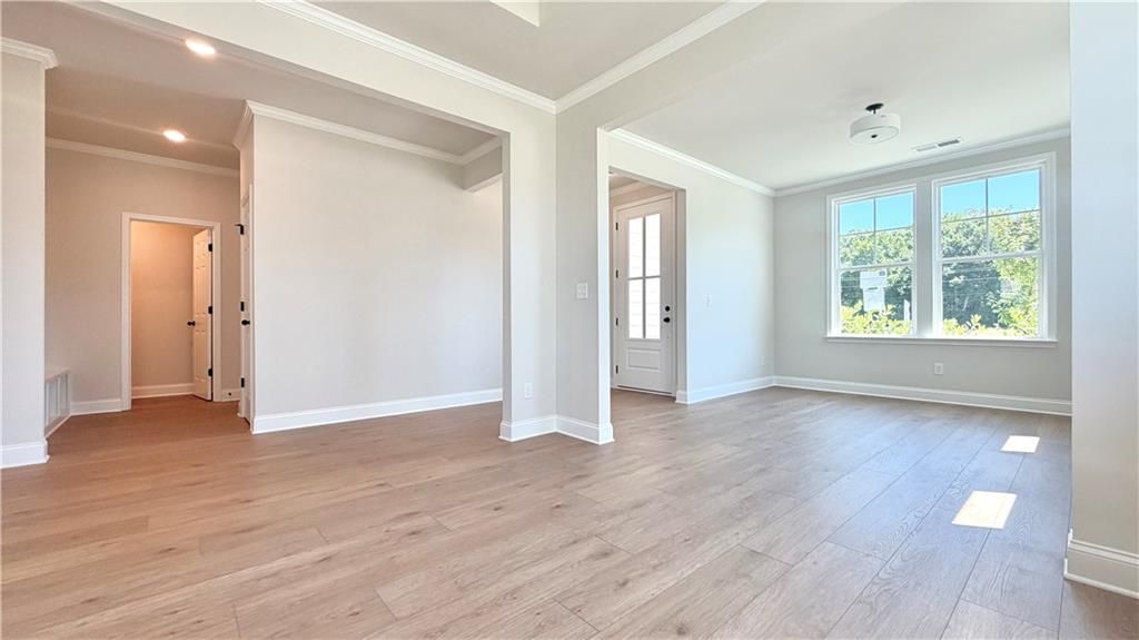 Bright open-concept living area with wood-style flooring in The Glenwood A floor plan at Wehunt Meadows, Hoschton, GA.