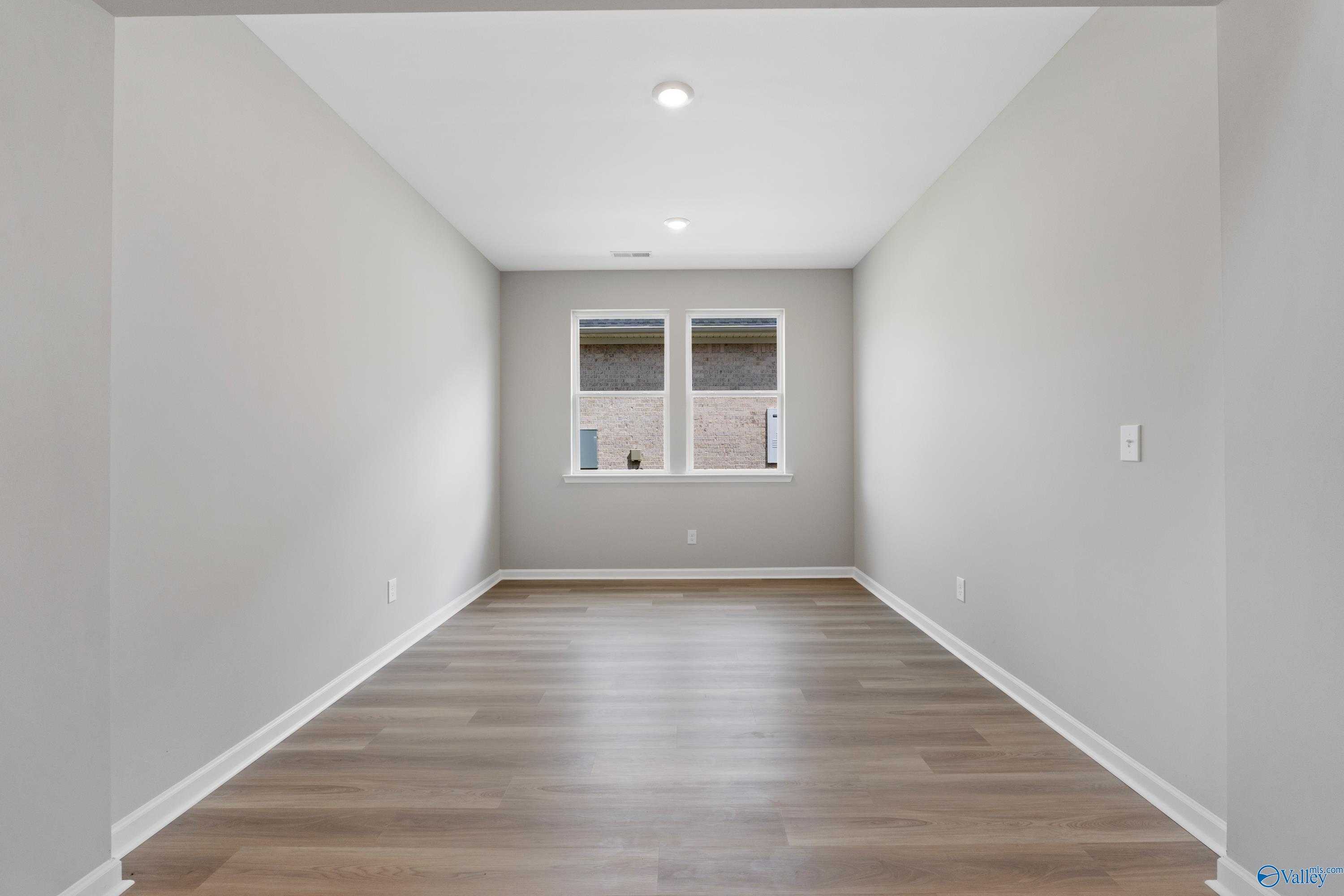 Spacious empty bedroom with gray walls, large windows, hardwood floors in The Dorado by Davidson Homes, Huntsville AL