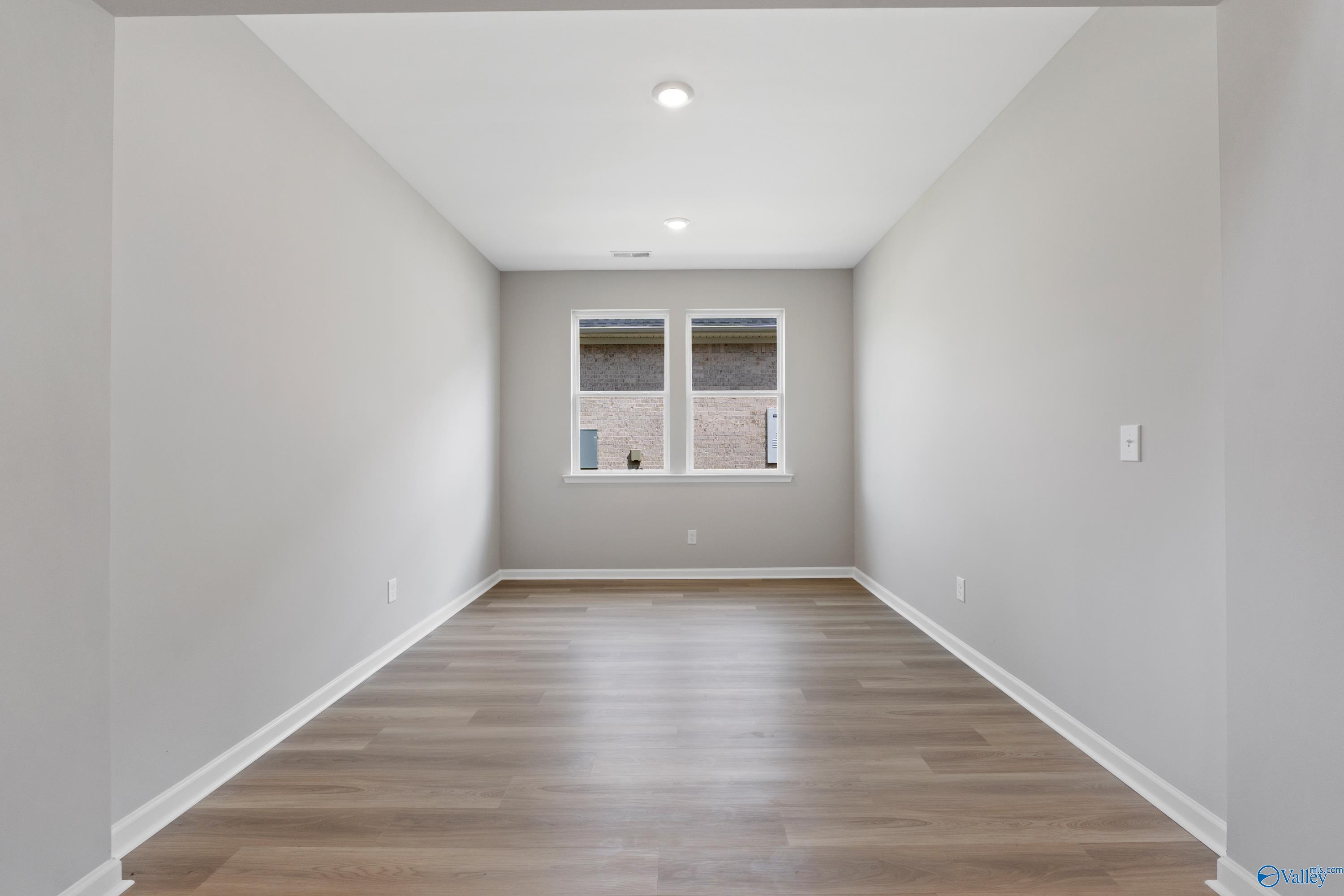 Spacious empty bedroom with gray walls, large windows, hardwood floors in The Dorado by Davidson Homes, Huntsville AL